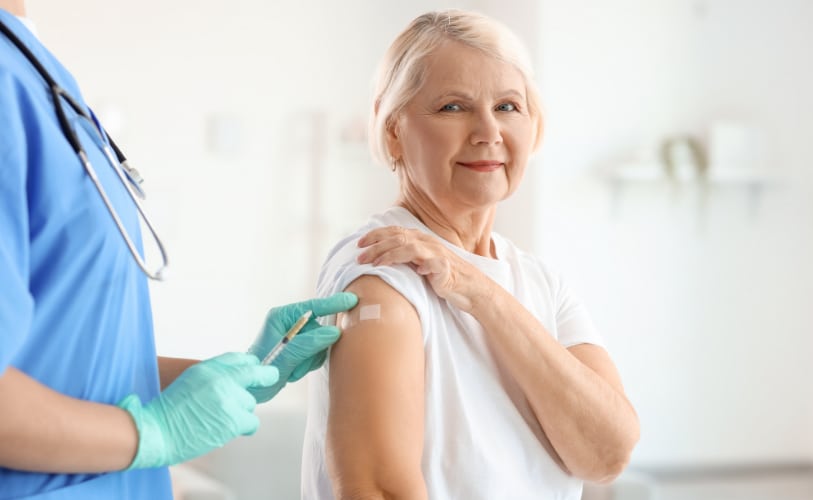 Older woman receiving an upper-arm vaccination from a healthcare professional